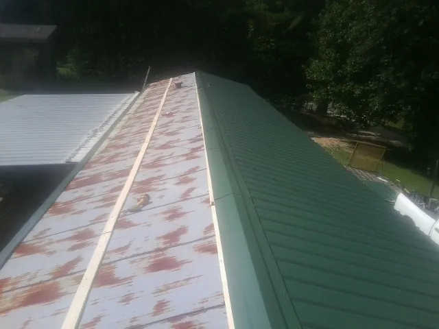 Old rusted panels beside newly installed green metal roofing — Wind Damage Roof Repair by Roofing Brothers in Orrtanna
