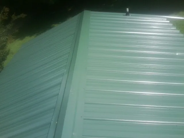 New green metal panels meeting at the ridge of a roof — Flat Roof Repair work by our crew in Orrtanna