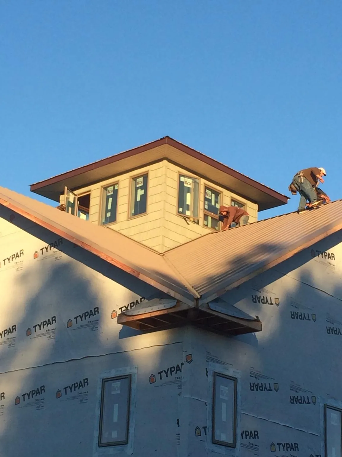 Roofers working around a rooftop cupola on a new metal roof at sunset — Roof Waterproofing in Orrtanna by Roofing Brothers